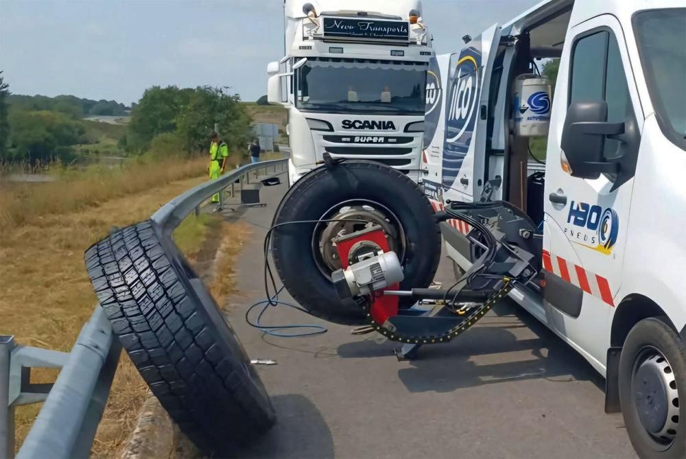 Pneu de poids-lourd maintenu par un mécanisme attaché à un fourgon de dépannage